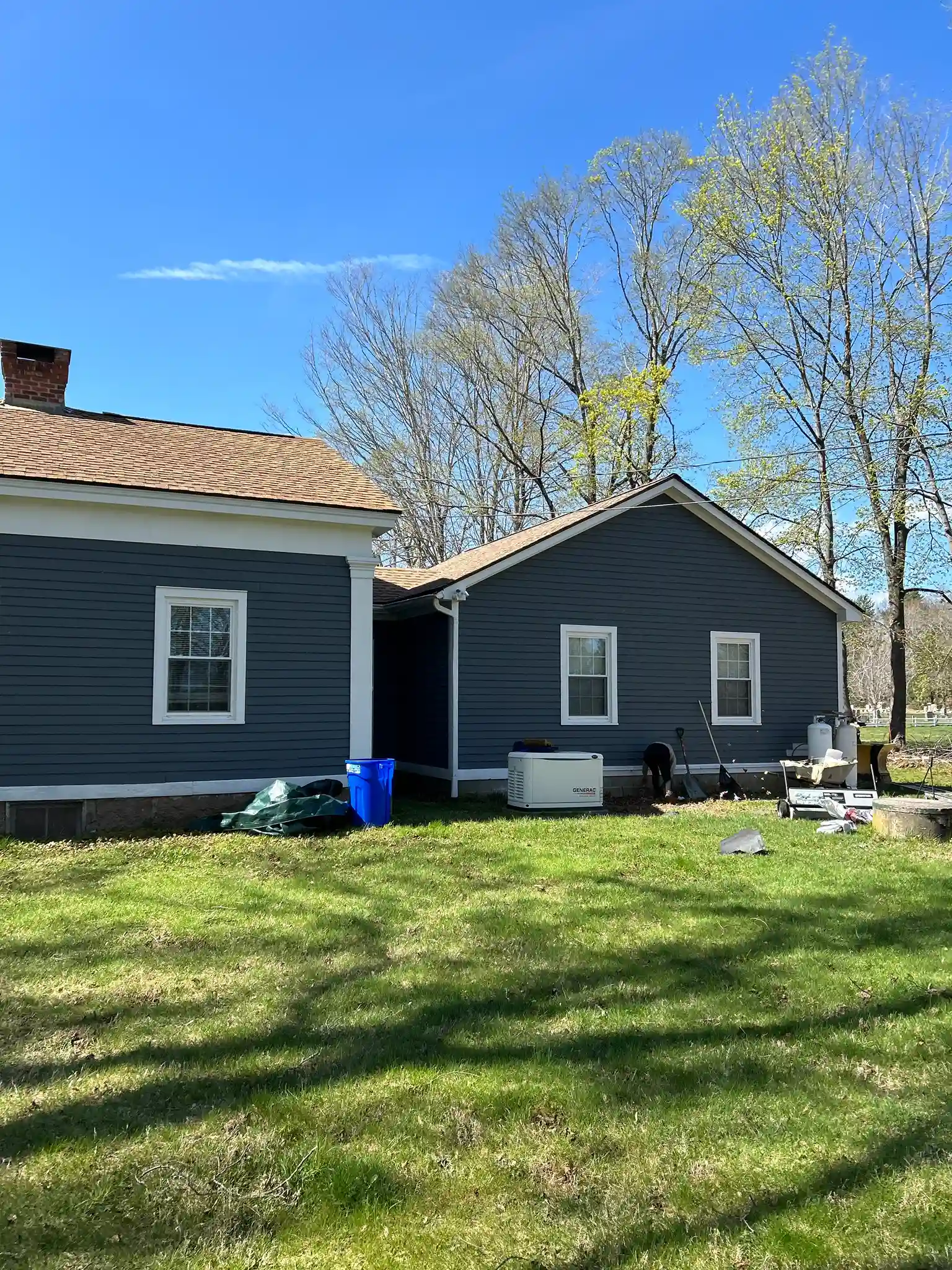 Roofing team performing residential roof replacement on house in Hopkinton Rhode Island with shingles being installed